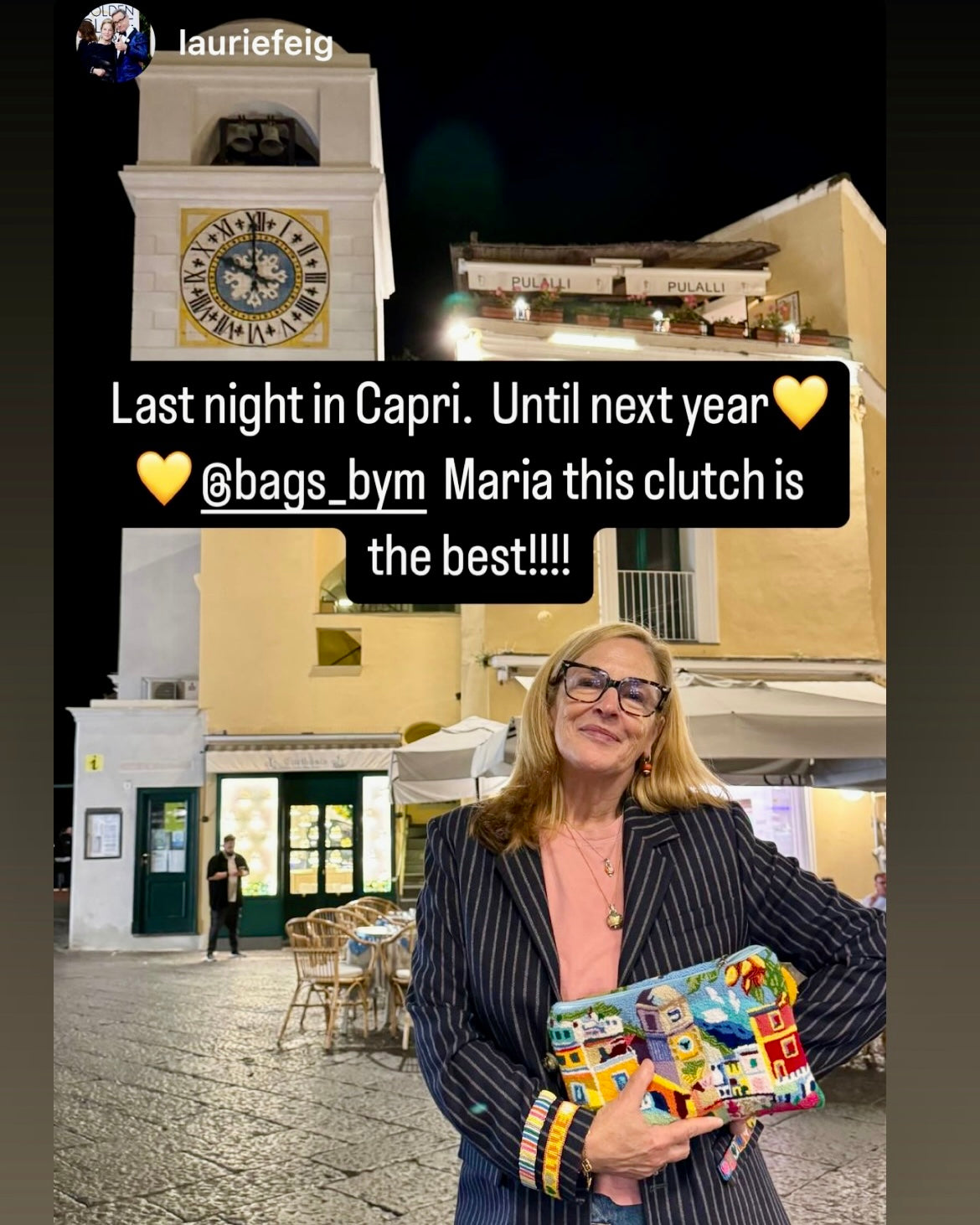 Laurie Fieg holding a colorful clutch By Maria Marigliano Caracciolo in front of a clock tower in Capri