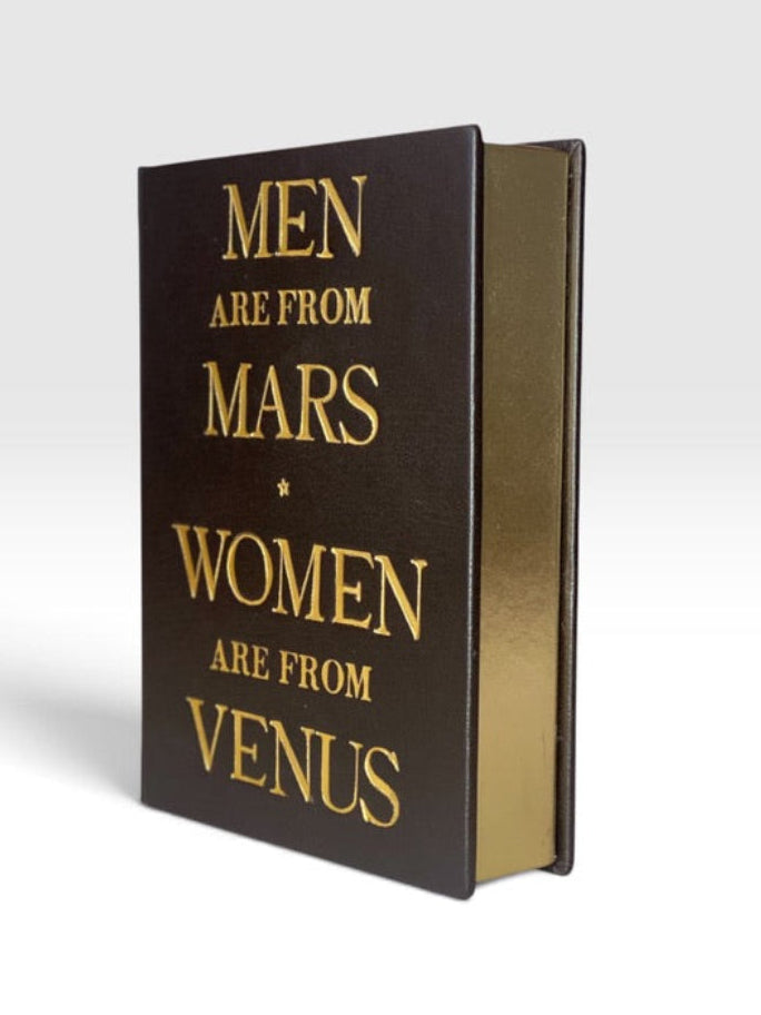  book clutch with a dark brown cover and gold foil lettering that reads 'MEN ARE FROM MARS * WOMEN ARE FROM VENUS', shown standing upright on a light gray background. By M. Design Maria Marigliano Caracciolo